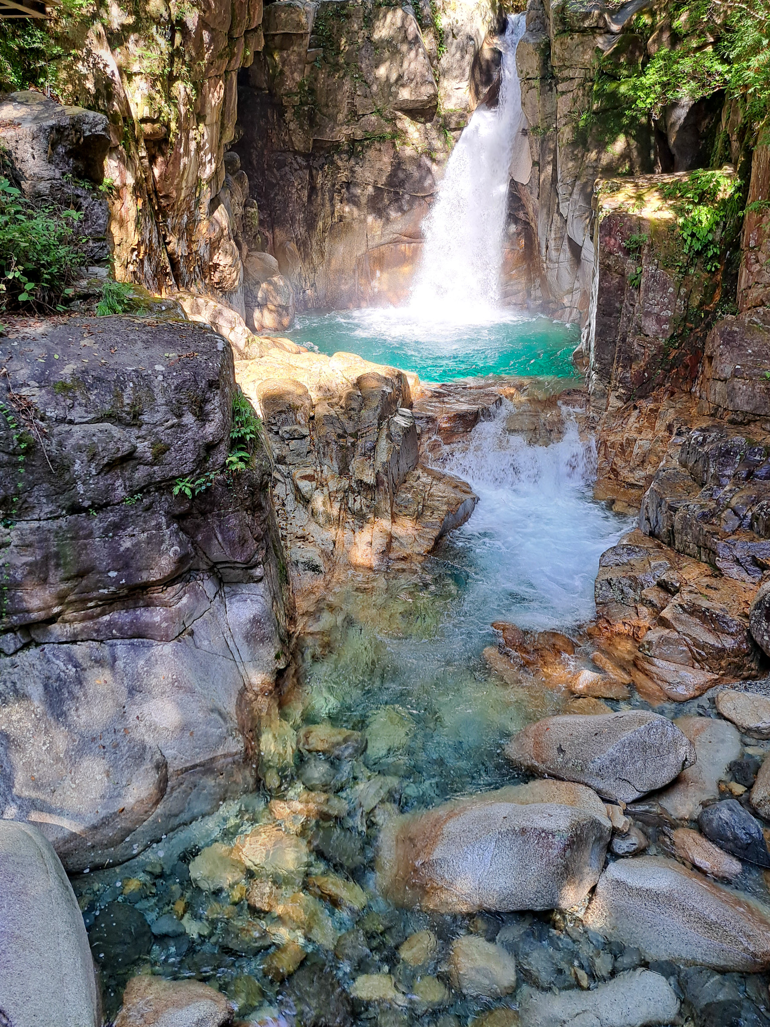 Wasserfall mit türkisem Becken im Bergwald